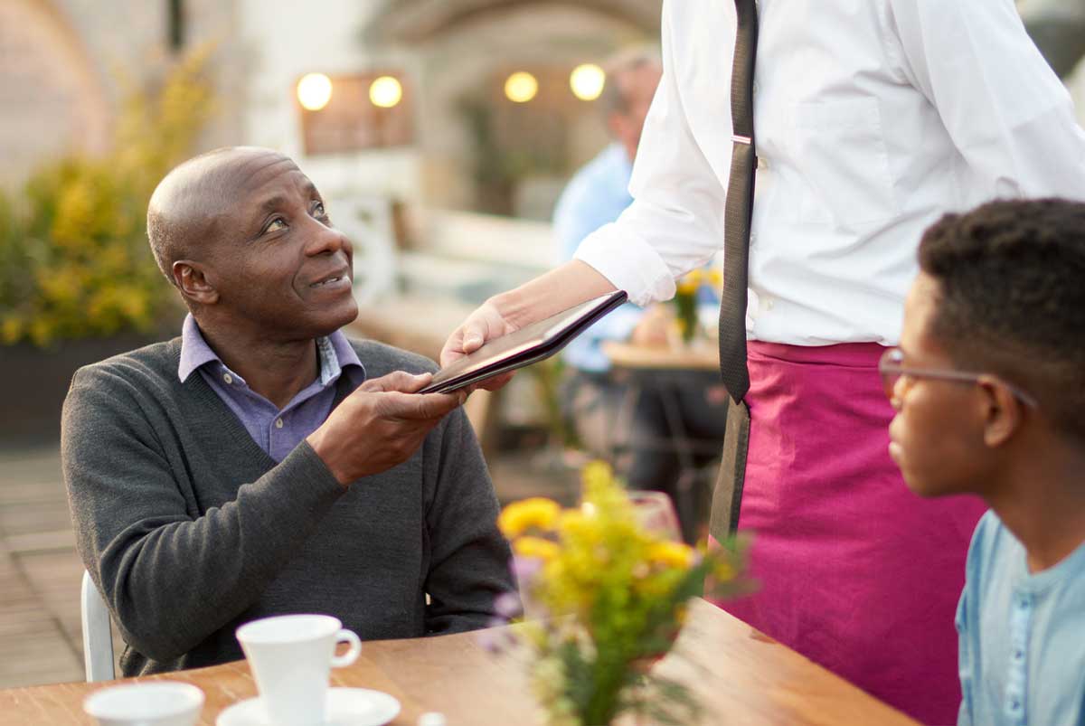 man handing restaurant check to waitress