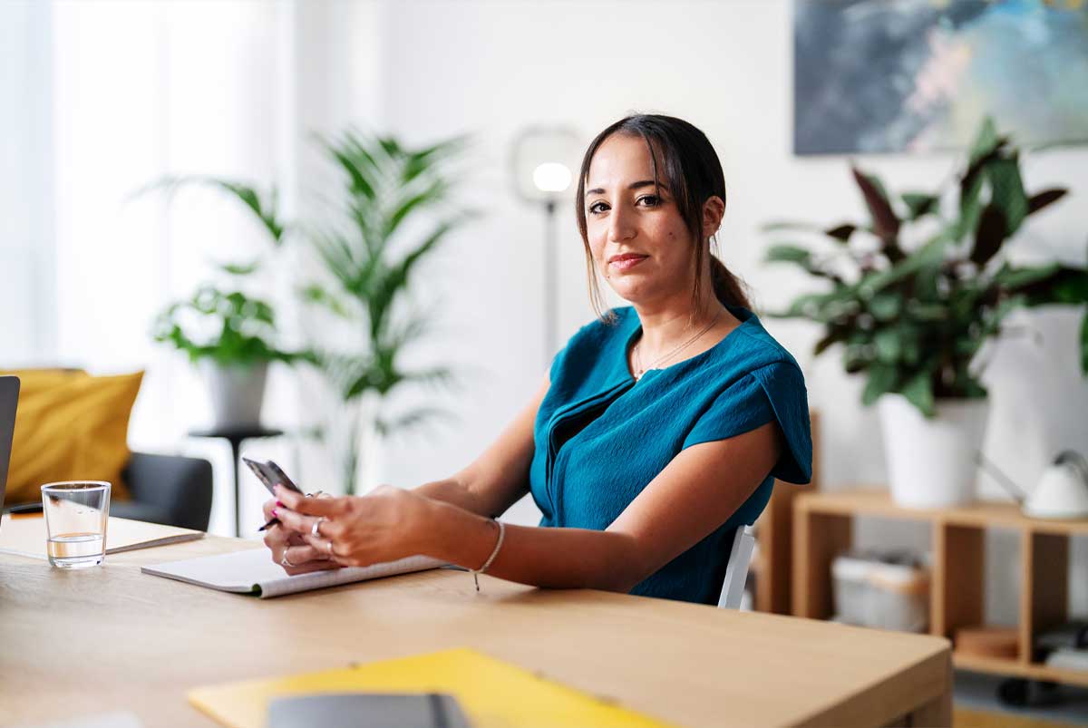 Woman at table with notebook and phone