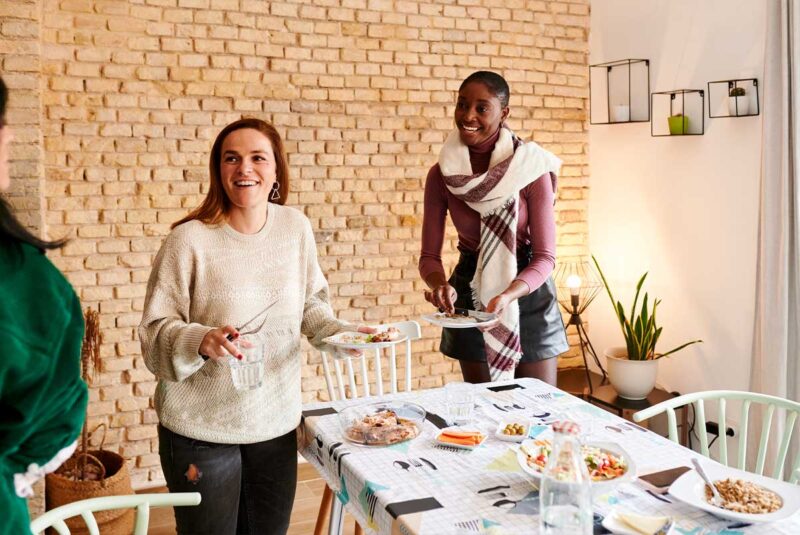 Two friends set a table in a home they bought together.