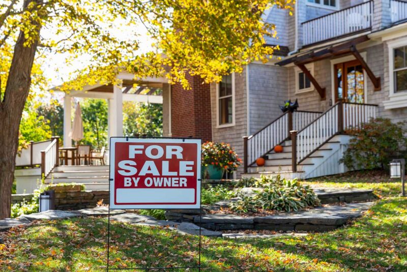 A home with a "for sale" sign in the front yard.