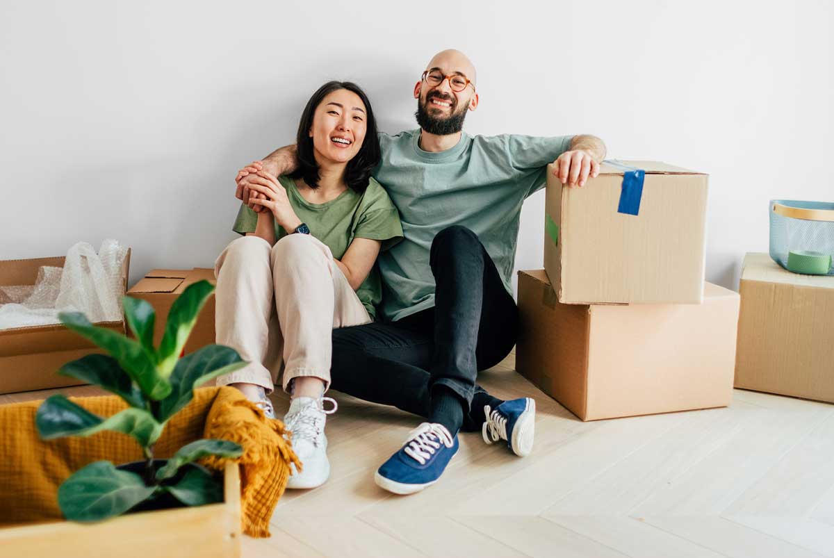 A young couple rest together on a pile of move-in boxes.