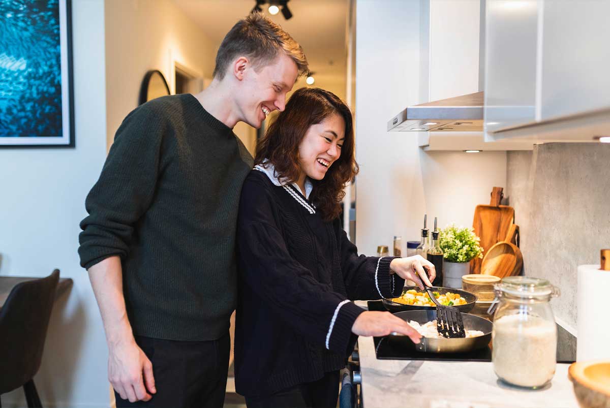 Man and woman cooking together in the kitchen at the stove in their home