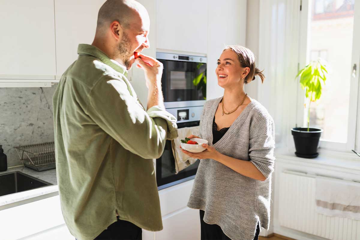 A young couple laughs in a house they are renting-to-own.