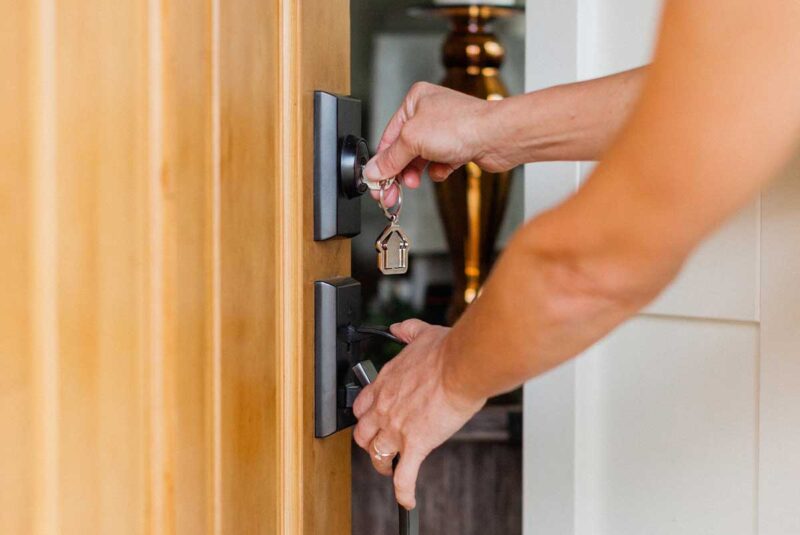 A new home with a key turning the lock of the front door.