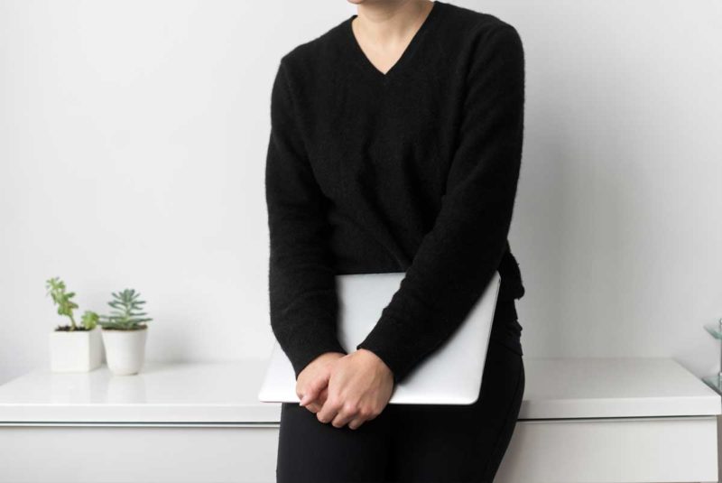 Person in black leaning on white shelf