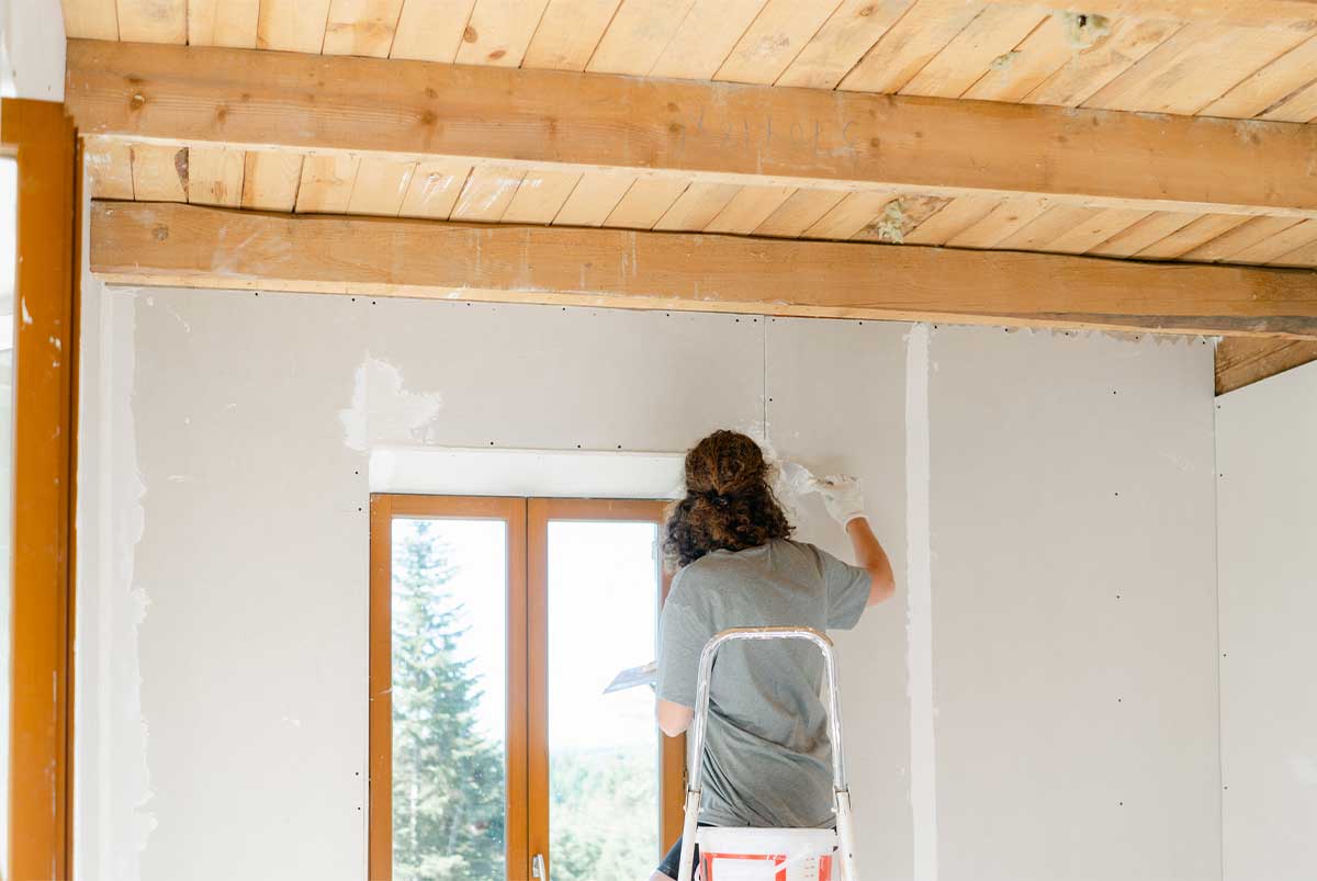 Woman painting wall with a fresh coat of white paint