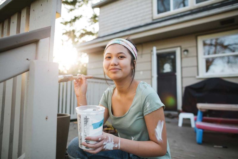 young woman painting deck railing