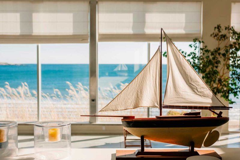 Sailboat model on a desk overlooking the ocean