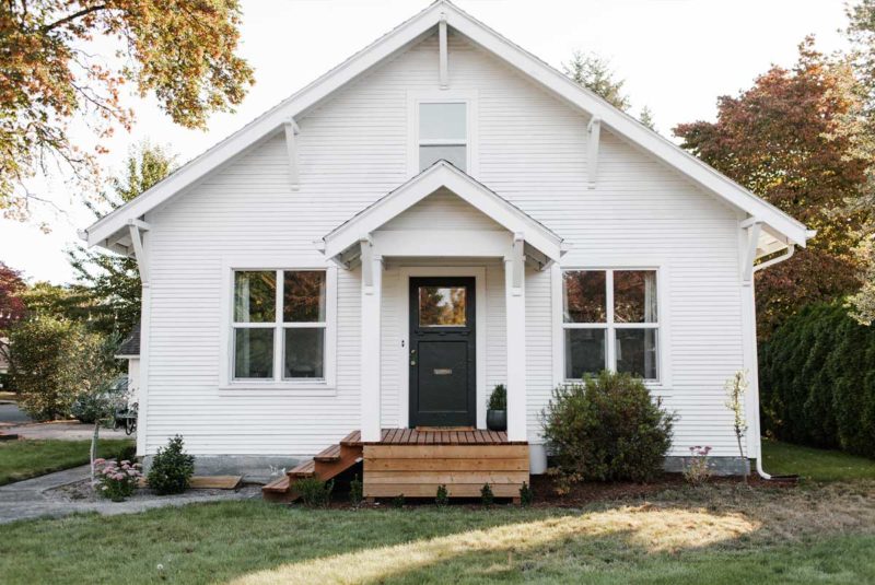 Small white traditional home on grass