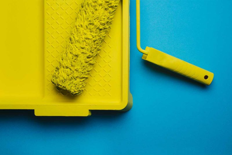 Yellow paint roller in a yellow paint tray