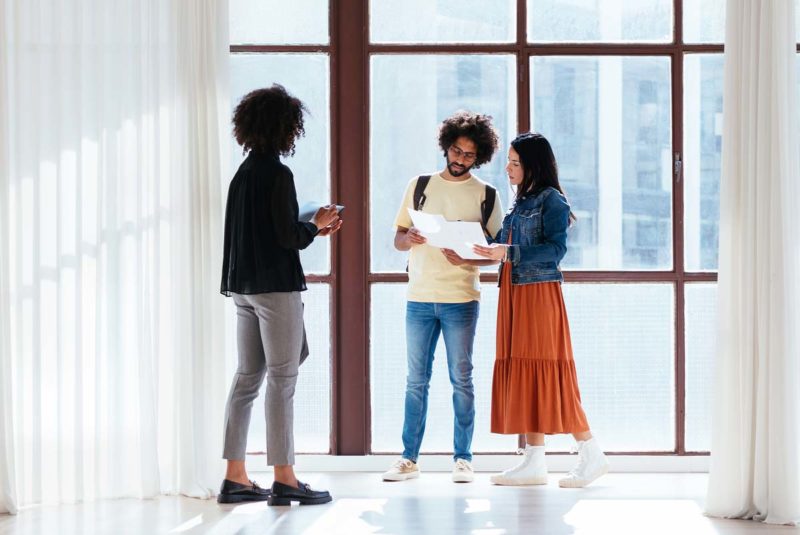 Young couple and real estate agent looking at contract