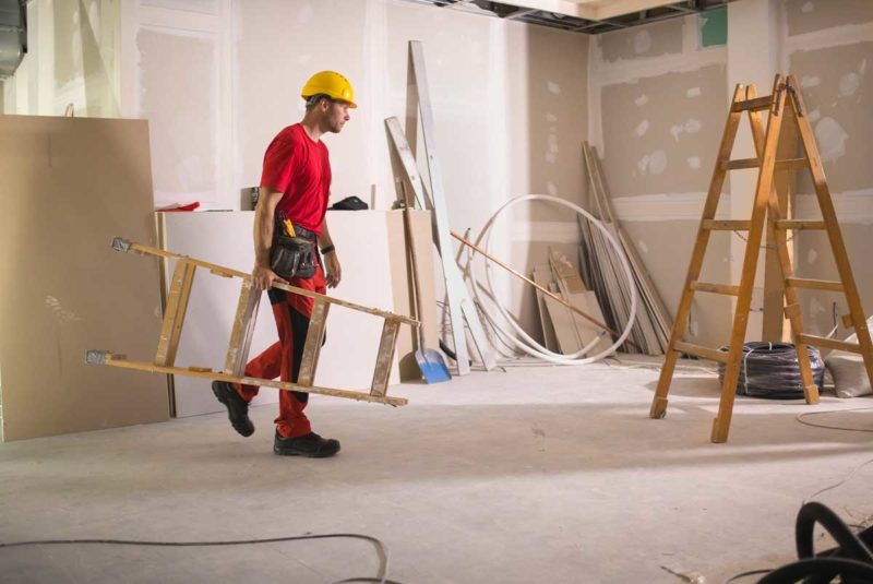 Construction worker carrying ladder