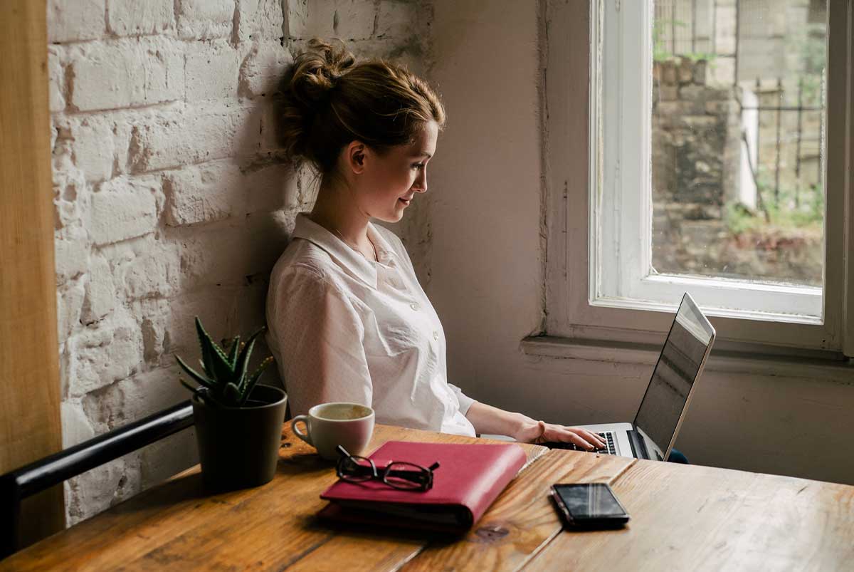 Woman sitting with her laptop drinking coffee