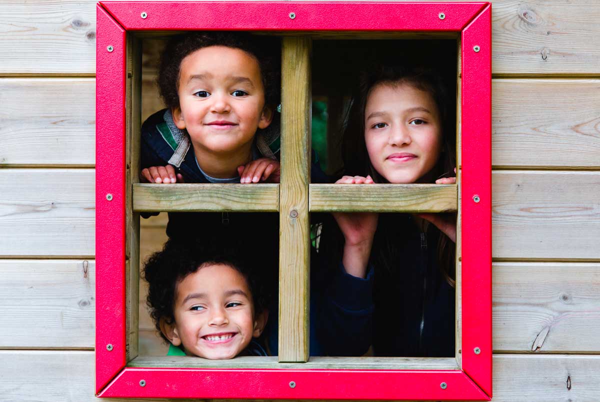 Three siblings looking out playhouse window