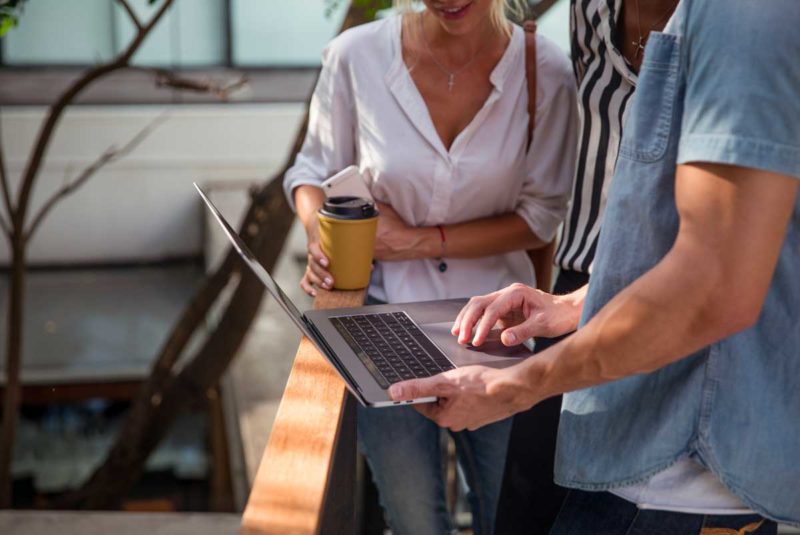 Man and woman on balcony looking at computer