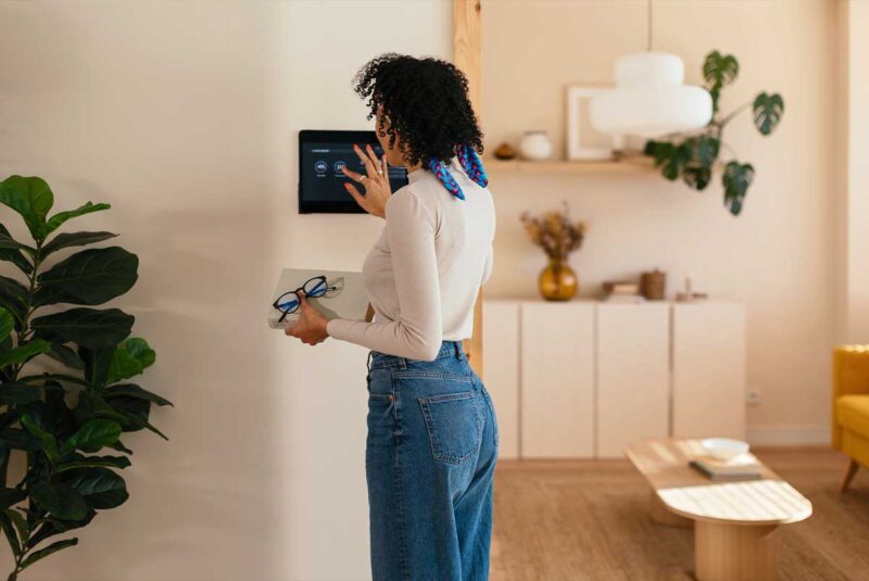 A woman adjusts the thermostat in her home.