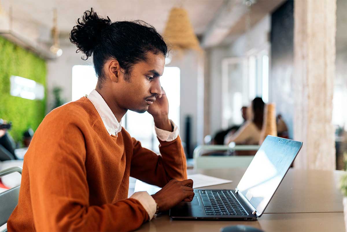 A man in a cafe browsing on his laptop