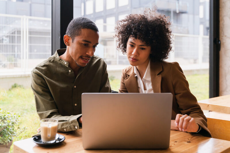 A young couple reviews personal loan benefits on a laptop.