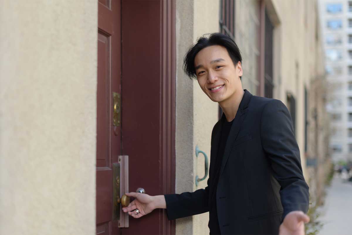 Man standing outside a door with his hand on the doorknob