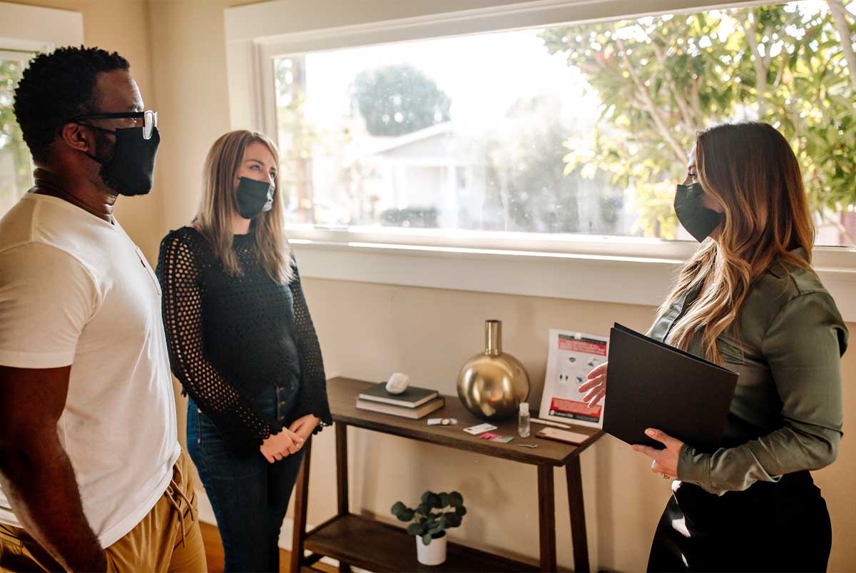 Three people in masks standing by a window